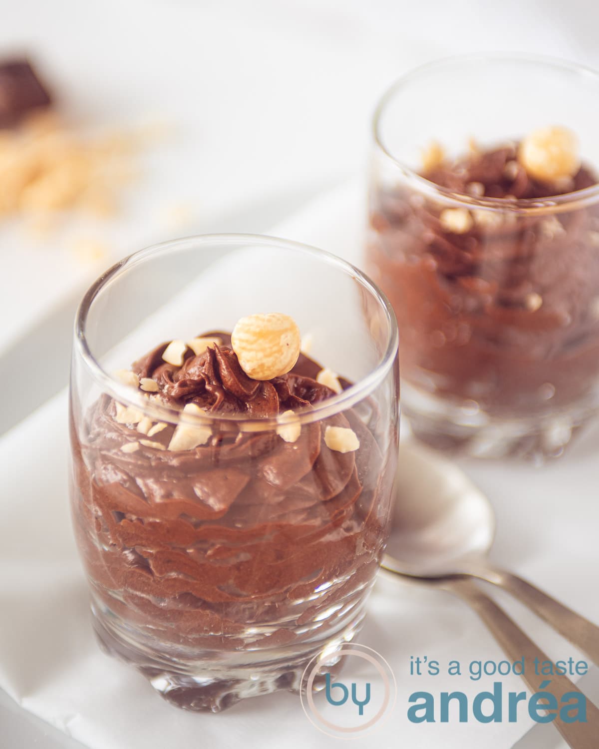 Two glasses filled with dark chocolate mousse and hazelnuts