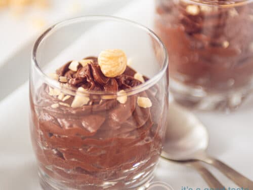 Two glasses with chocolate mousse topped with hazelnuts, square