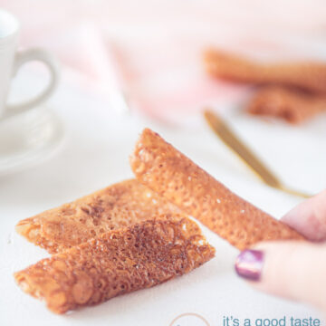 honey tuiles on a white background. A hand taking one of them.