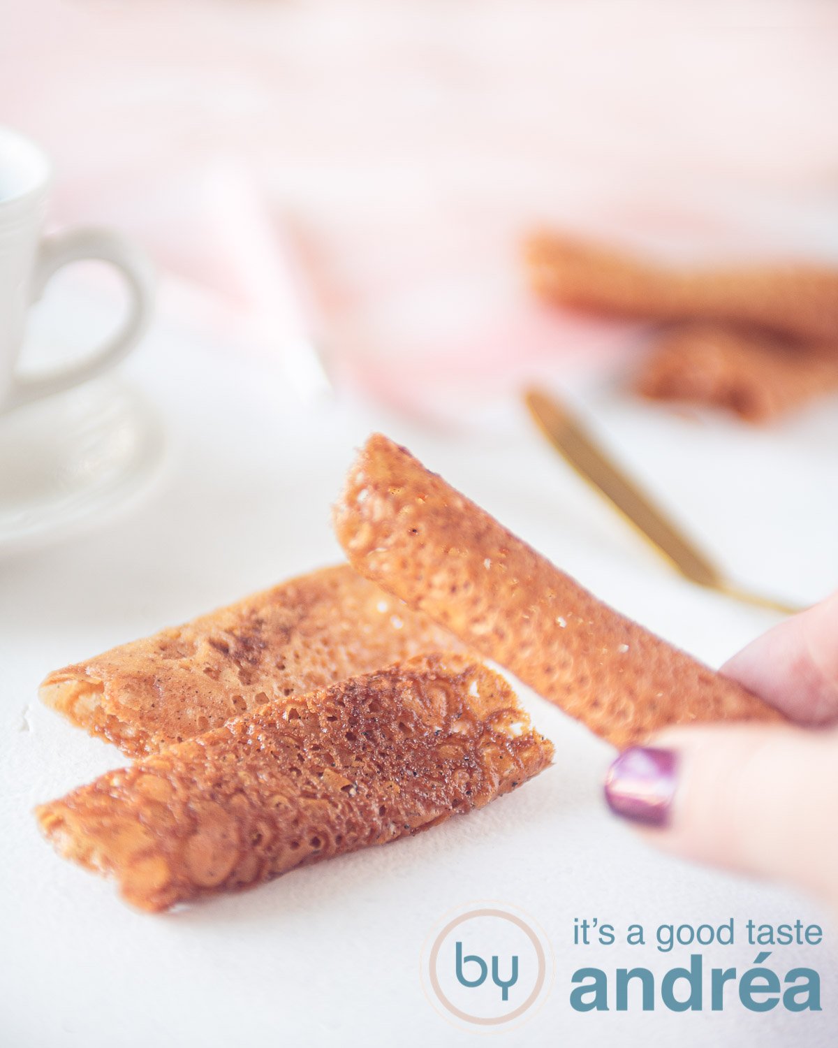 honey tuiles on a white background. A hand taking one of them.