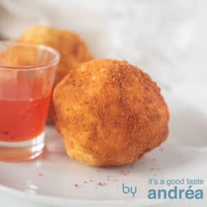 a square photo with papas rellenas and a glass filled with chili sauce