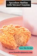 A pink plate with a speculaas muffin with streusel, a bite taken out. A text on top: speculaas muffins with streusel topping