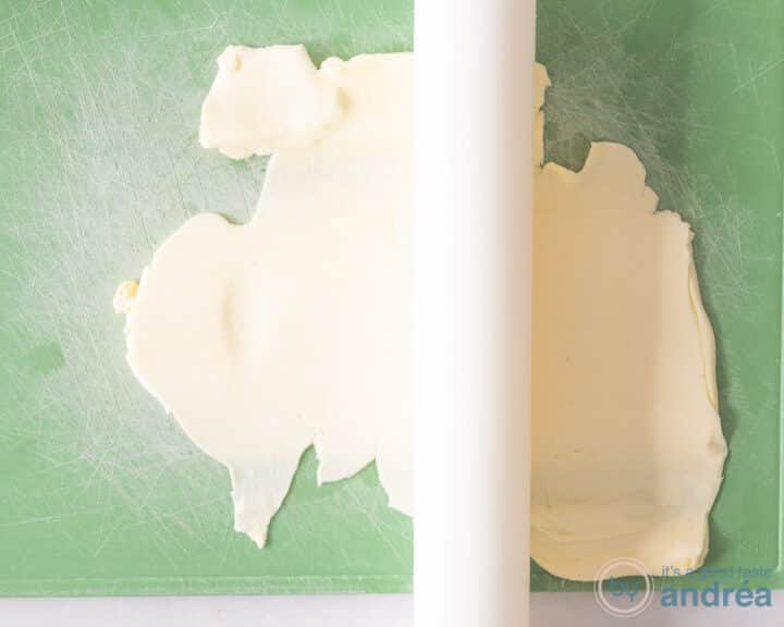 Butter being rolled out on a green board with a white rolling pin.