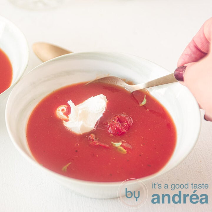 Square cut of a bowl of soup with Italian tomato soup with mascarpone. One hand takes a bite