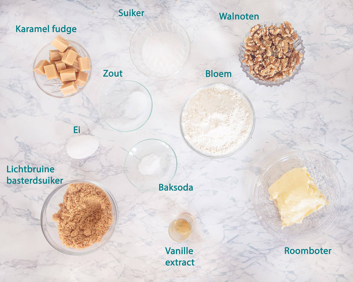 Ingredienten Walnootkoekjes met Karamel op een witte marmeren achtergrond. Een tekstbeschrijving van de ingrediënten staat erbij.