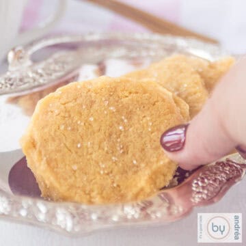 A square photo showing part of a silver platter with a cookie with a hint of ginger. A hand takes a cookie.