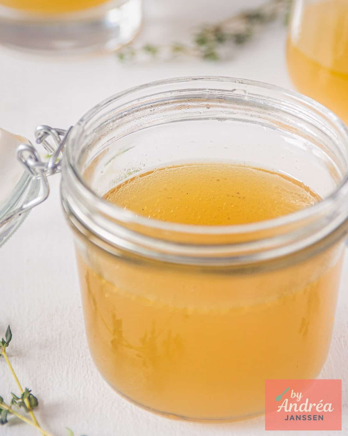 A jar with chicken stock, homemade parts of others in the background