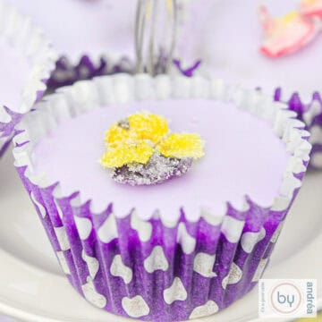 A square photo featuring a lavender cupcake with a yellow violet sugar flower.