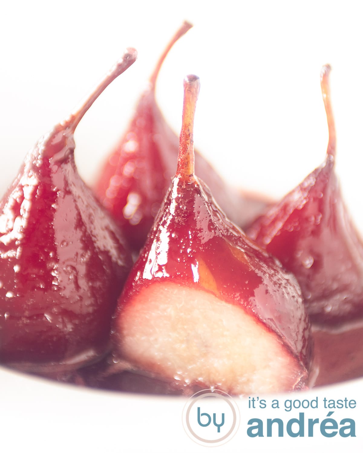 4 stewed Pears au vin rouge aka poached pears with syrup in a white deep plate