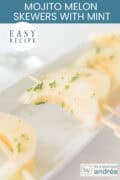 A portion of a white bowl with melon slices marinated in mojito and mint. A caption at the top reads: "Easy recipe, Mojito Melon Skewers with Mint."