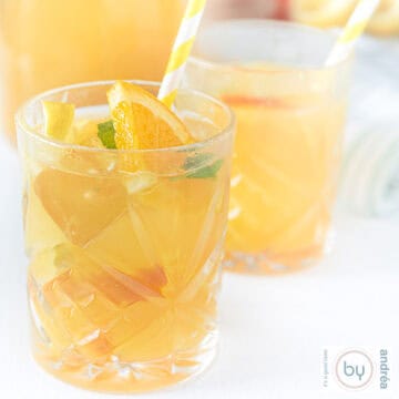A square photo with two glasses of iced tea with lemon and mint in front of a carafe.