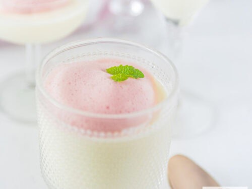 Square photo of buttermilk panna cotta in a glass with berry foam topping