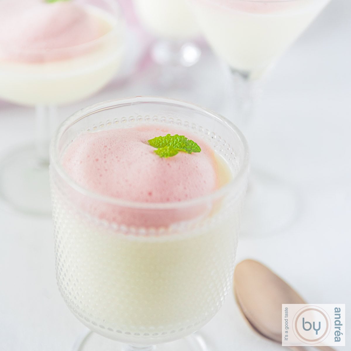 Square photo of buttermilk panna cotta in a glass with berry foam topping