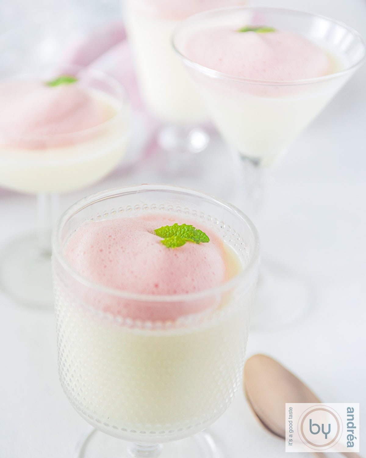 Een paar glazen met panna cotta karnemelk met bessensaus in een glas.