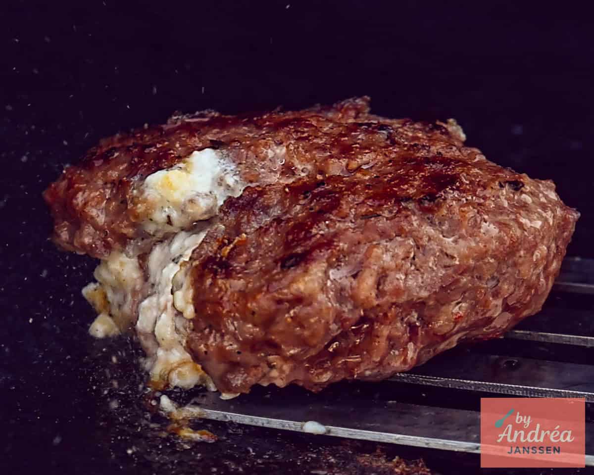 Een BBQ waarop de gevulde hamburger wordt gebakken.