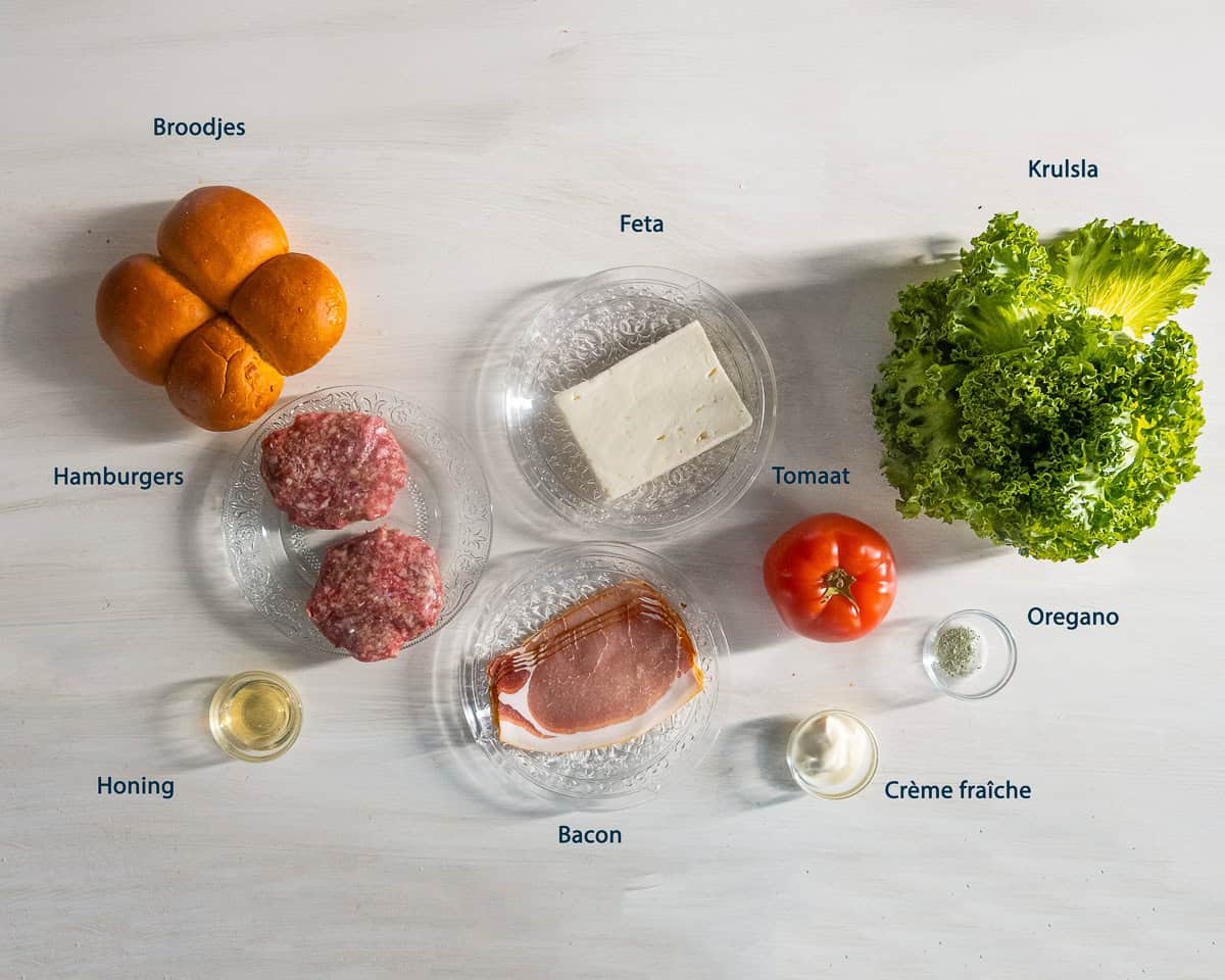 Ingredienten Broodje hamburger met feta en bacon op een witte ondergrond met tekst beschrijving.
