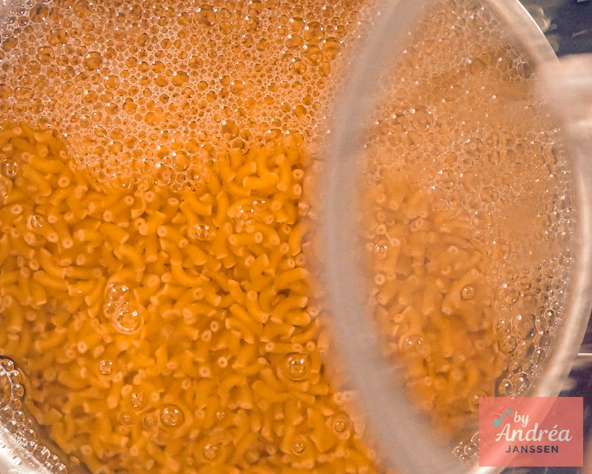 Elbow macaroni cooking in a pot of bubbling water.