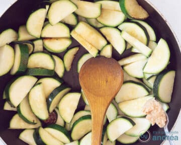 Garlic is added to a frying pan with zucchini slices.
