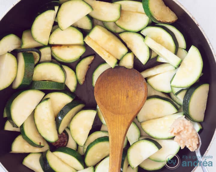 Garlic is added to a frying pan with zucchini slices.