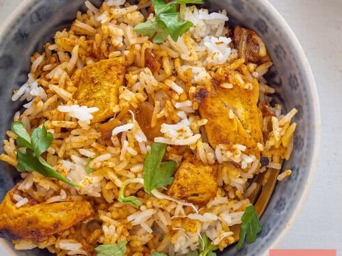 A square picture with a grey bowl filled with Indian Chicken Biryani