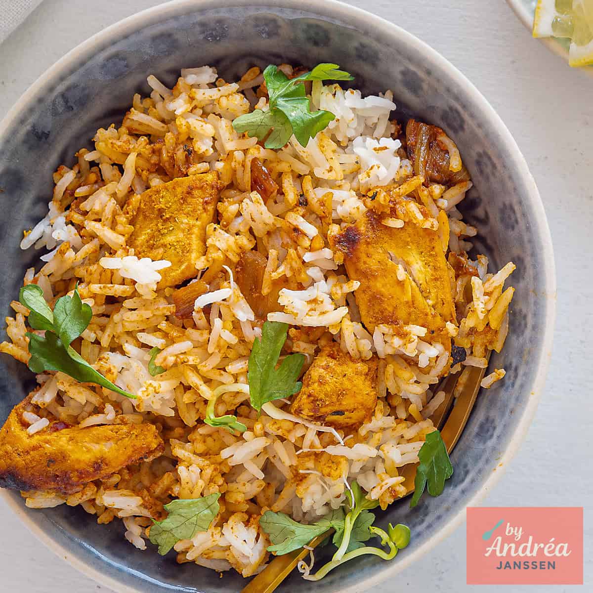 A square picture with a grey bowl filled with Indian Chicken Biryani