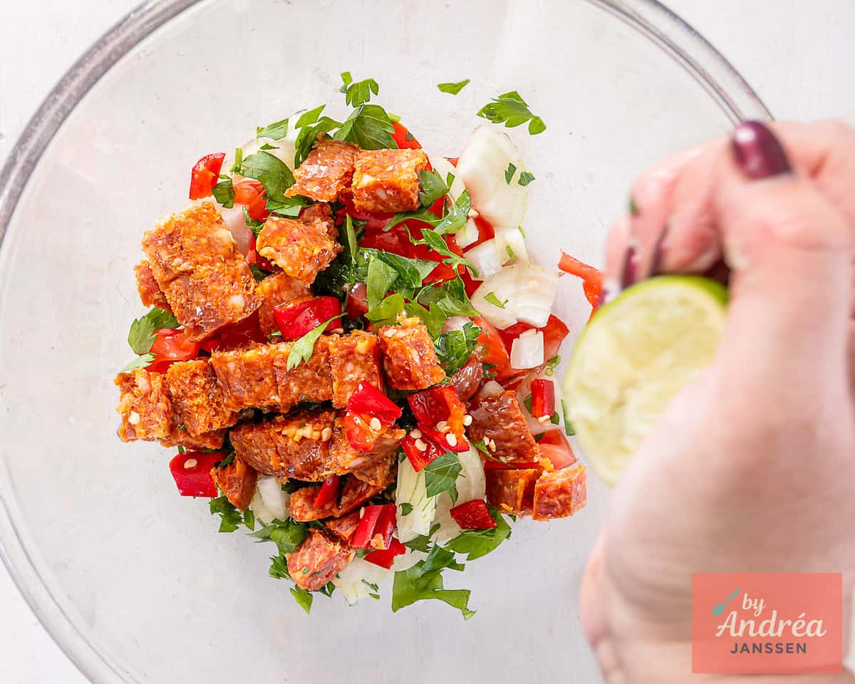 In a glass bowl the tomato filling with parsley, onion and chorizo is flavored with lime juice