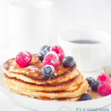 A stack of pancakes on a white plate with fresh fruit