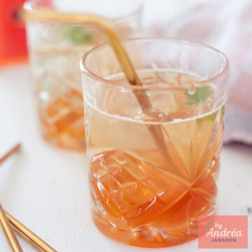 A square photo with two glasses of rosehip syrup diluted with water in a glass.