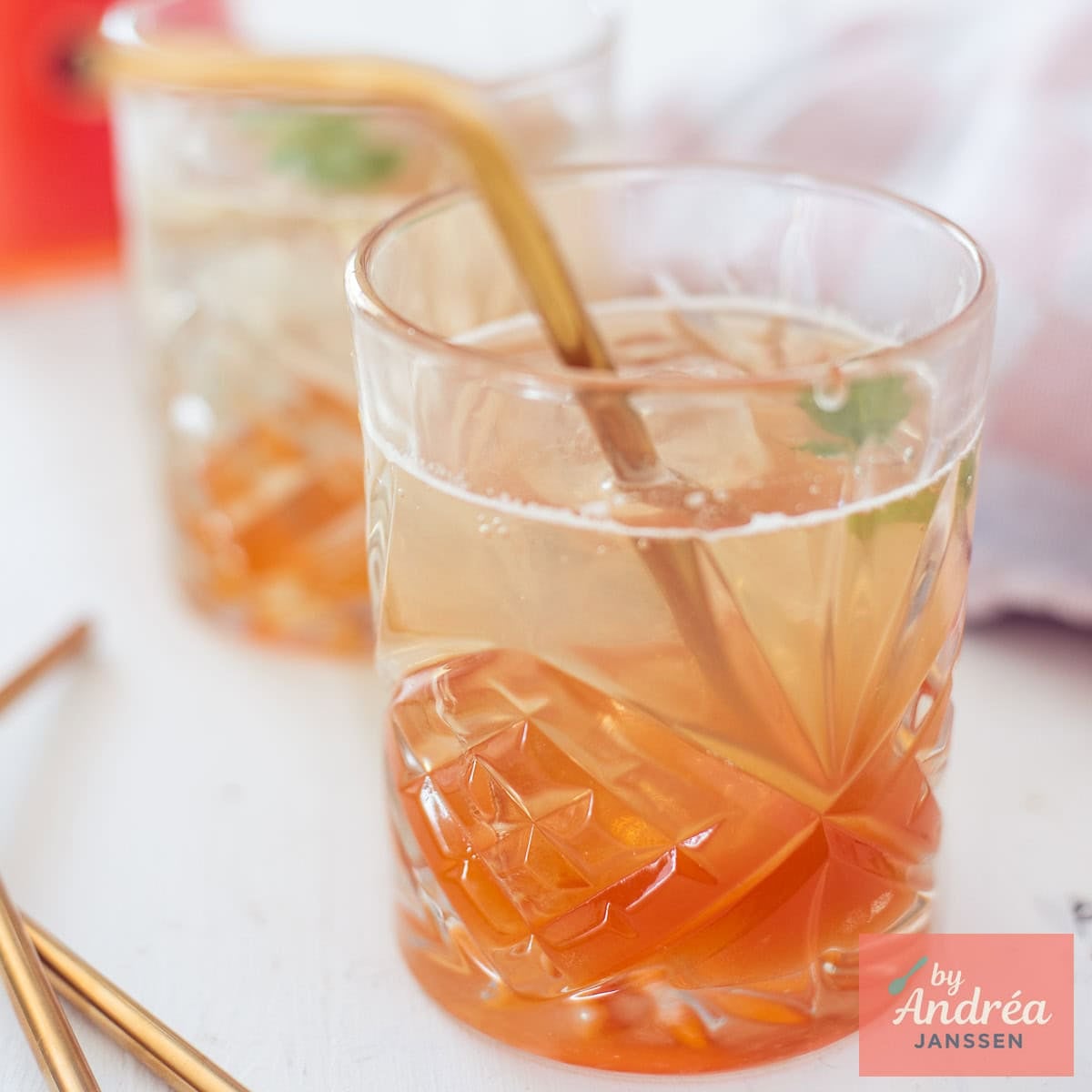 A square photo with two glasses of rosehip syrup diluted with water in a glass.