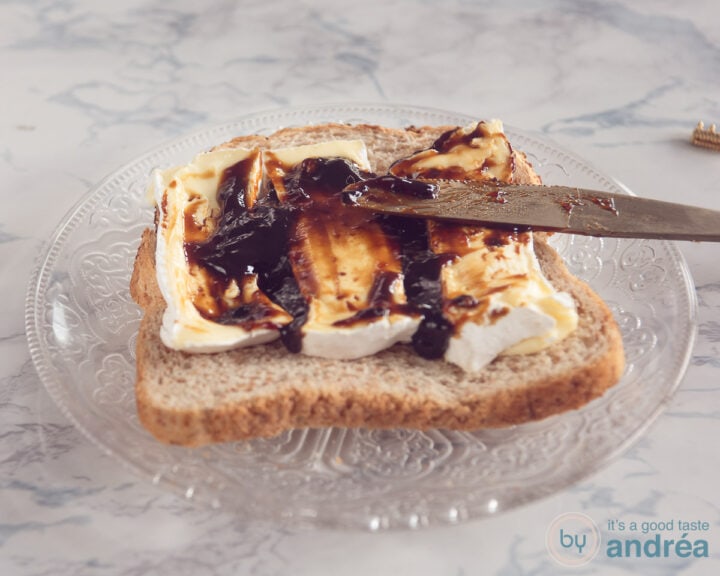 A slice of bread with slices of Camembert, apple syrup is spread on it