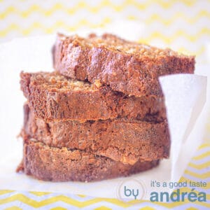 A square photo with 4 slices of stacked banana cake on a white baking paper. A yellow white background