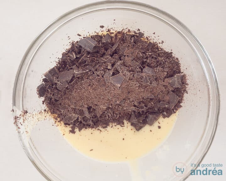 There is custard in a glass bowl to which chocolate is added.