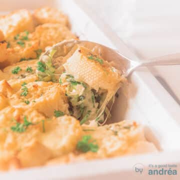 A square photo with a white baking dish. A scoop of chicken leek and a baguette are scooped out. Cheese gratin.