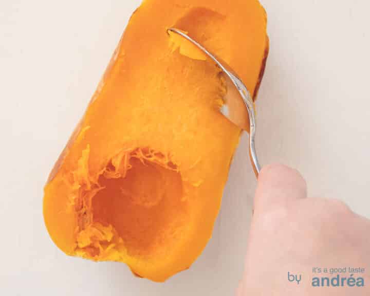 Half a roasted butternut squash is scraped out.