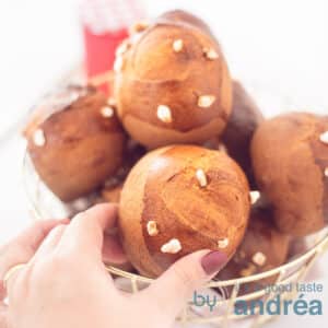 A square photo with a basket full of sugar balls with pearl sugar on a white background. A hand grabs a sandwich