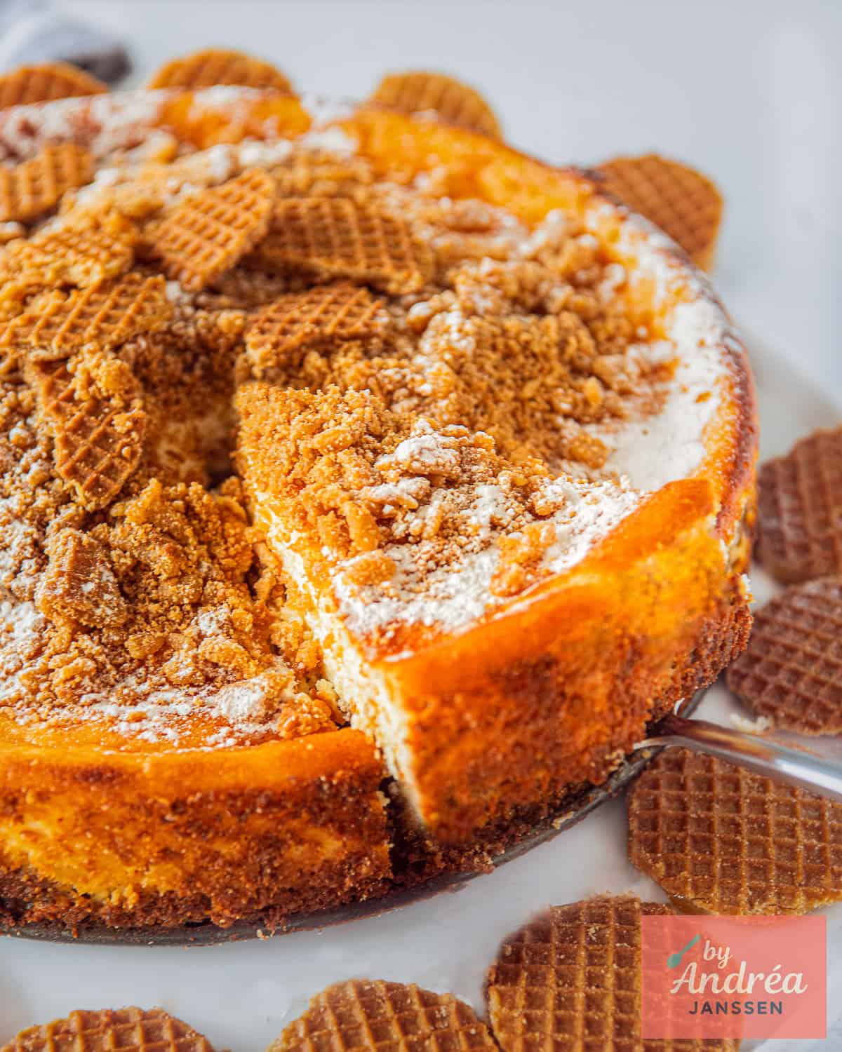 Een cheesecake met stroopwafels, waar een punt uit wordt geschept.
