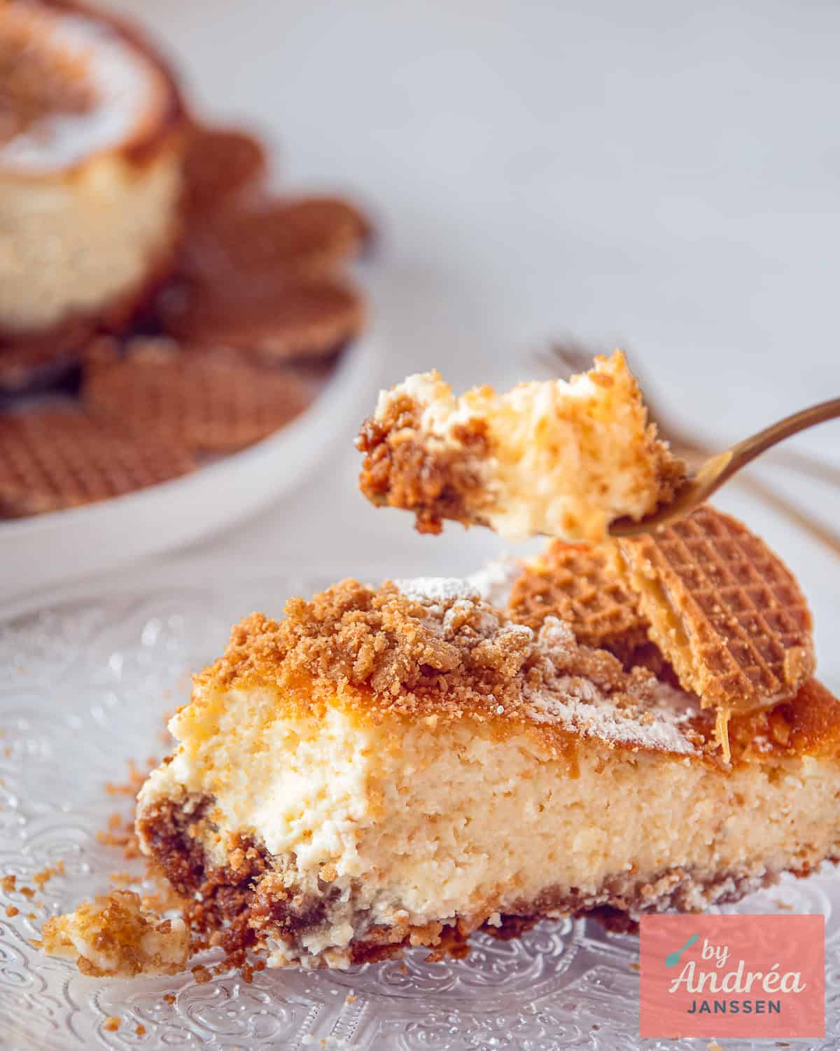 Een taartpunt met stroopwafel cheesecake waar een schep van wordt genomen.