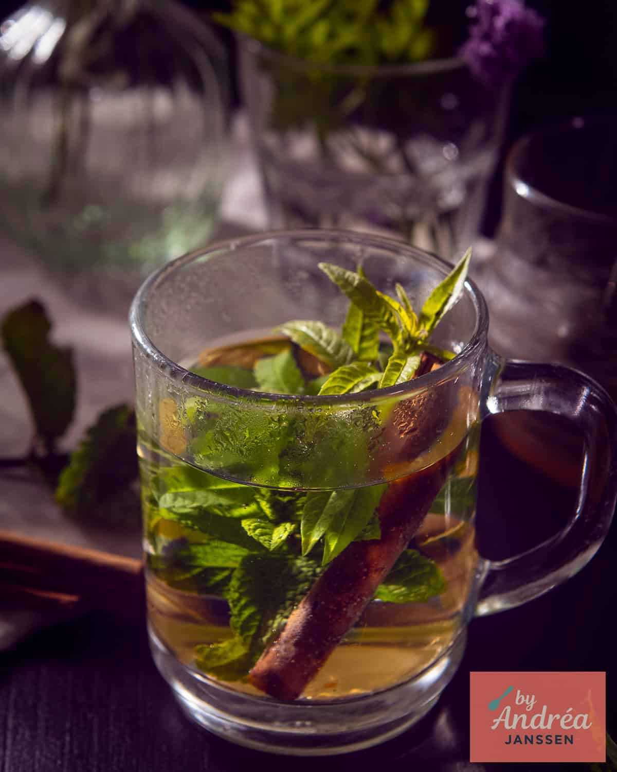 A glass with mint and lemon balm tea on a black background