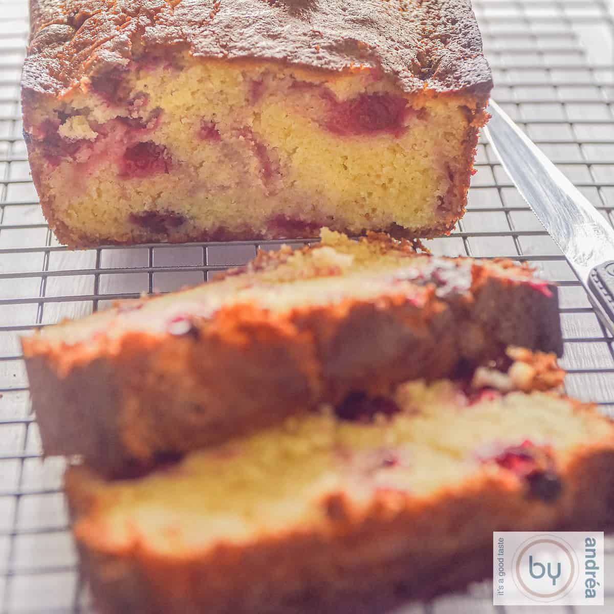 A square photo with a cake with two slices cut off filled with cranberries