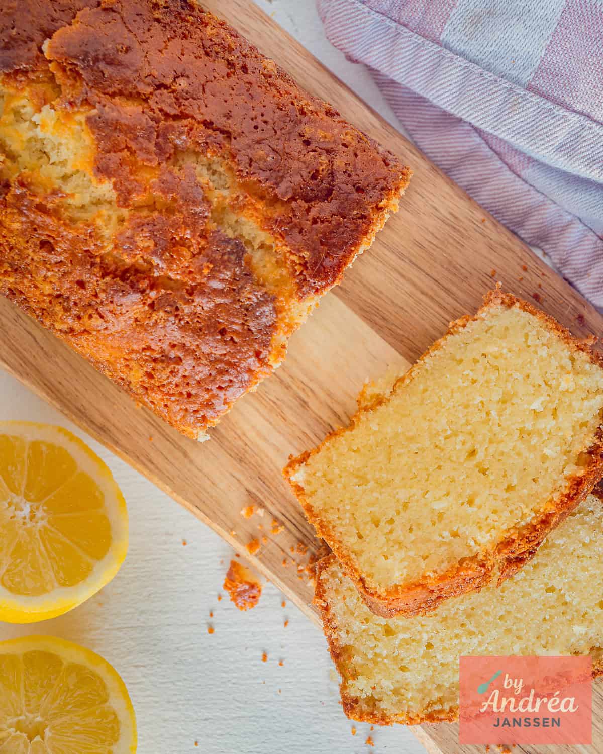 A loaf cake on a wooden board, made with lemon and olive oil. Two slices cut off.