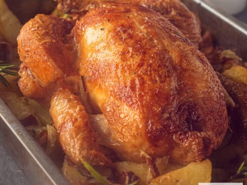 A square picture of a roasting pan filled with roasted chicken and potatoes, bacon and rosemary