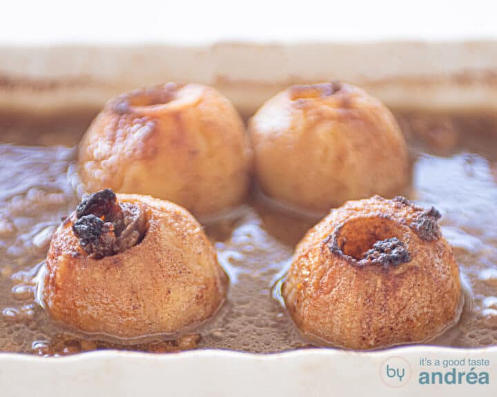 Baked apples in a caramel sauce in a white baking dish