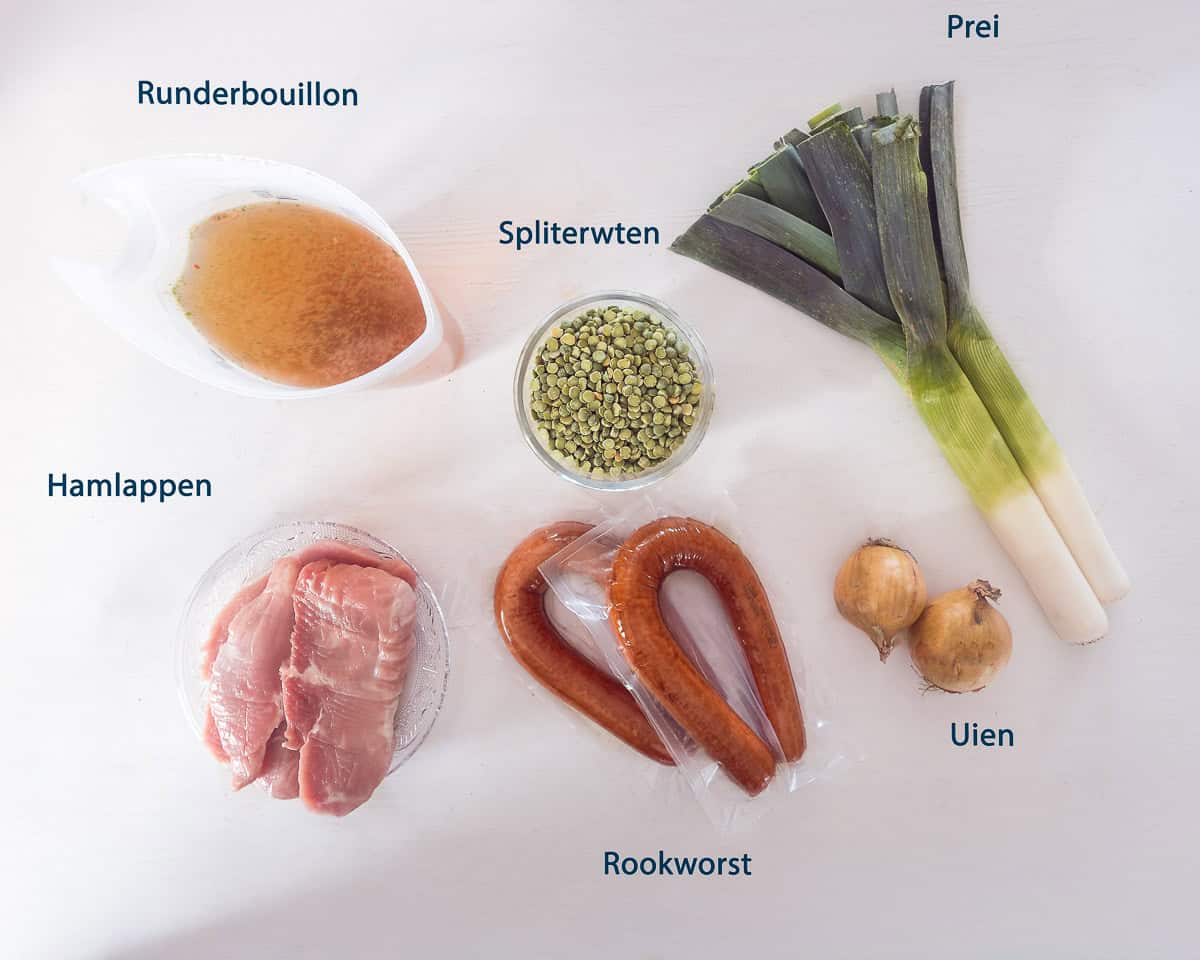 Ingredienten Ouderwetse Erwtensoep met Ham en Rookworst op een witte ondergrond met tekstbeschrijving.