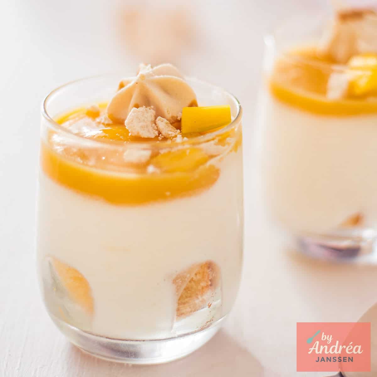 A square photo with two small glasses of White Chocolate Mousse with Mango Jelly