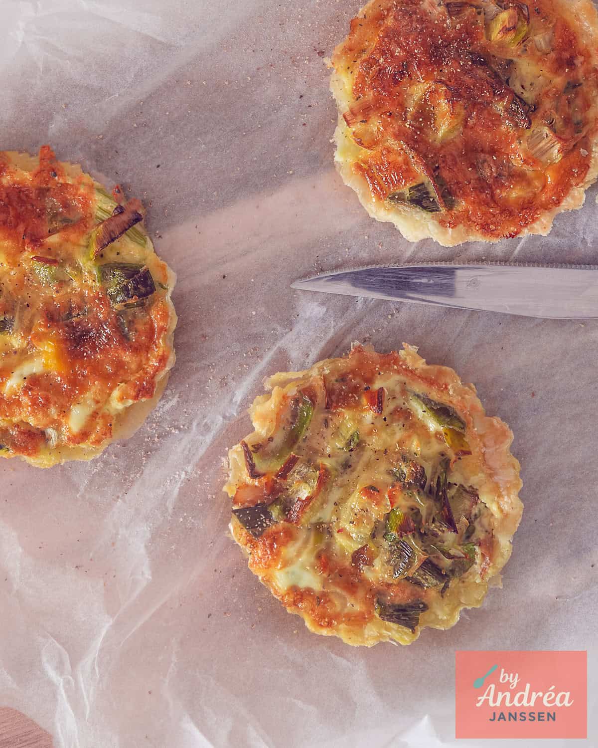 A top-down photo of three mini quiches with leek, mackerel, and thyme on white baking paper.