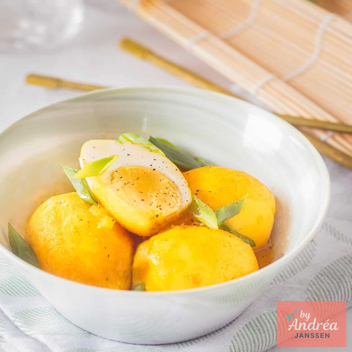 A green bowl with Indonesian style eggs in a coconut sauce