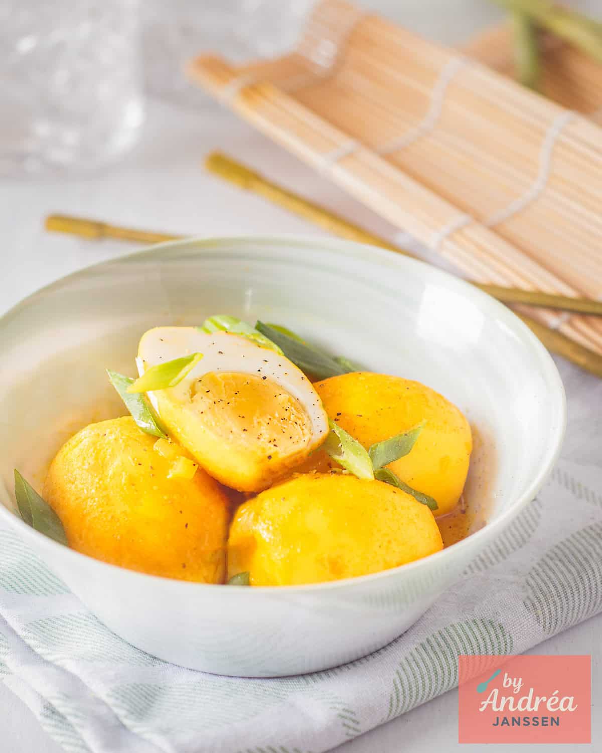 A green bowl with hard-boiled eggs stewed in a lemongrass galangal coconut sauce.
