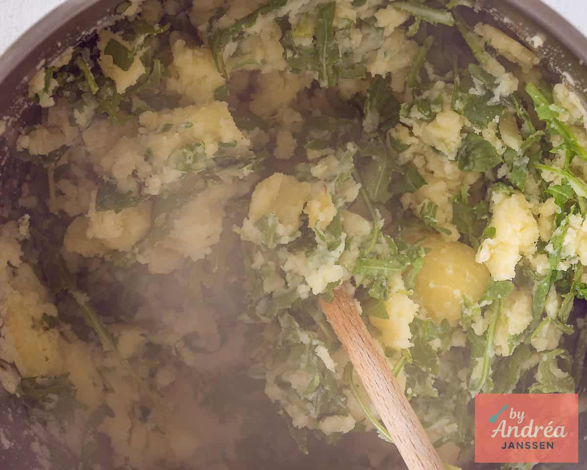 Rucola wordt door de aardappelpuree gemengd