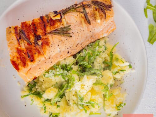 A square photo of mashed potatoes with arugula and grilled salmon