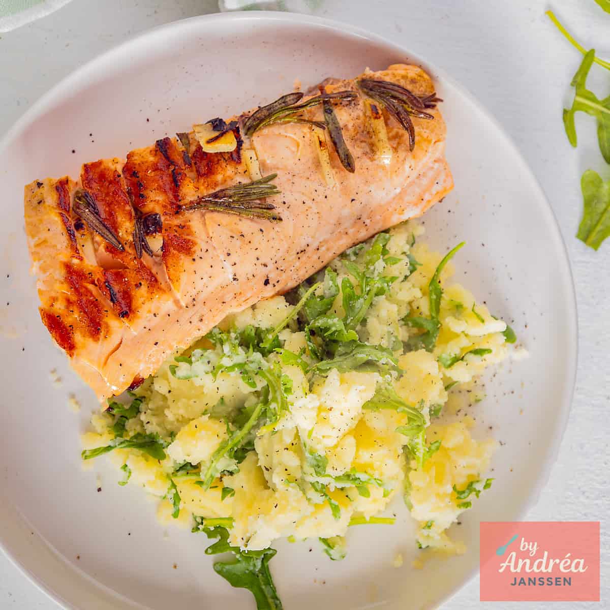 A square photo of mashed potatoes with arugula and grilled salmon